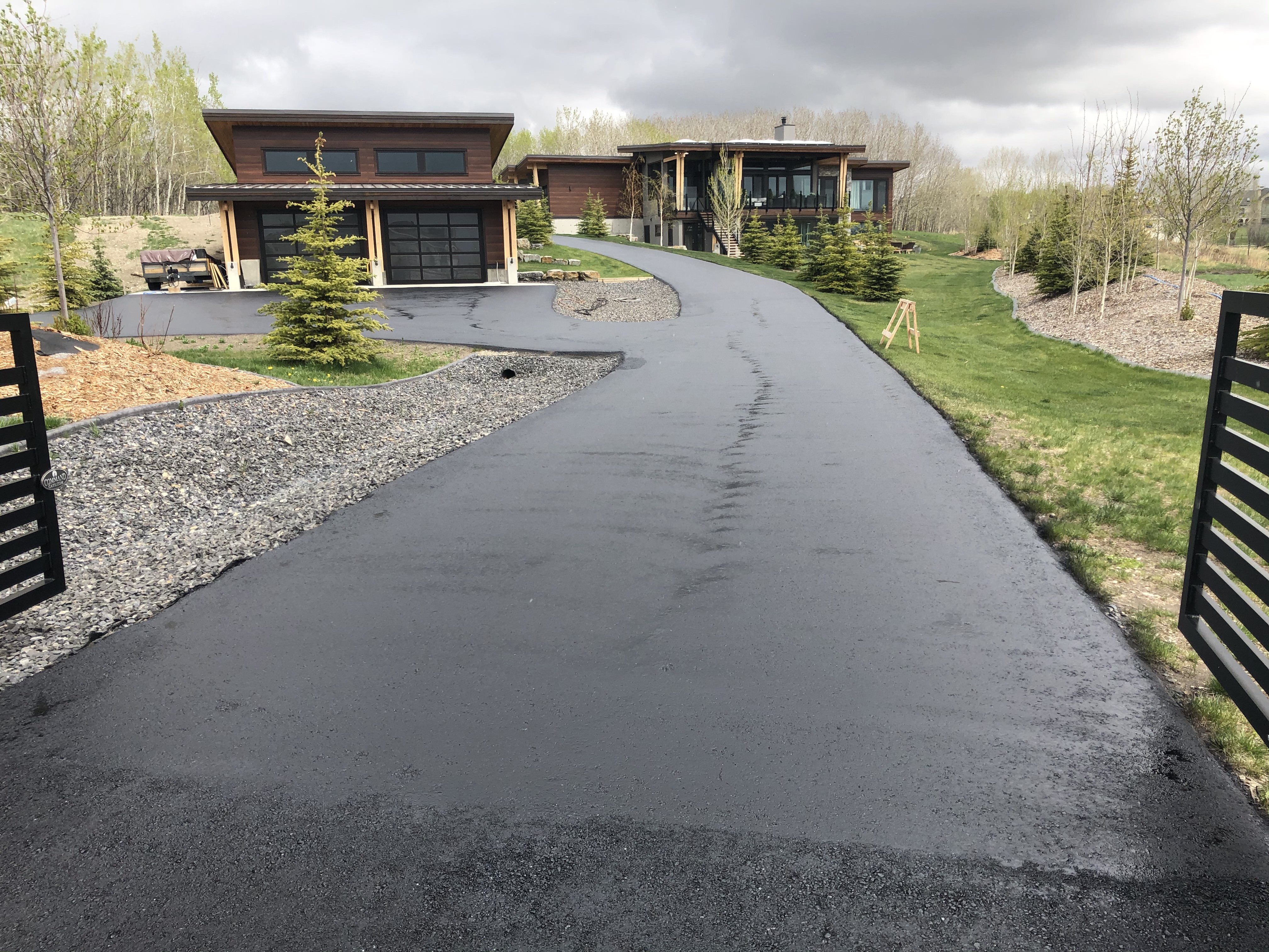 APC crew member applying black asphalt sealer to a residential driveway with a squeegee